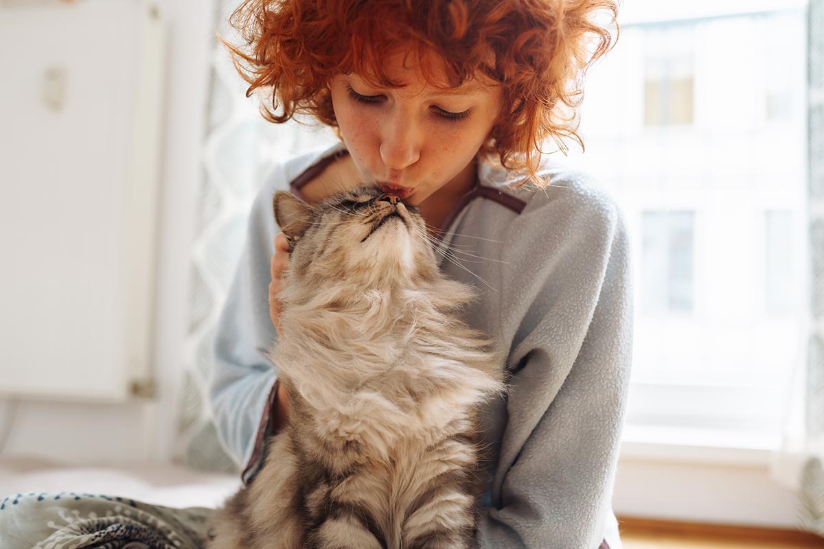 Happy Woman Kissing Cat On Nose